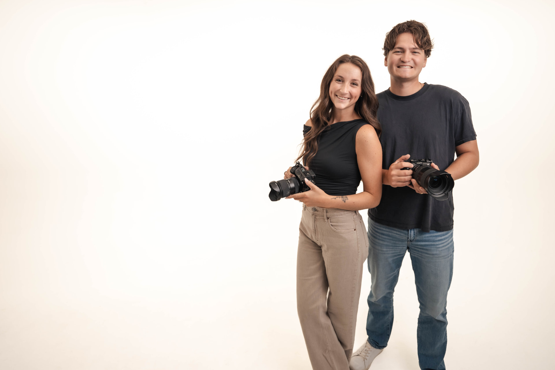 The Reids, a married wedding photography and videography team, holding their cameras